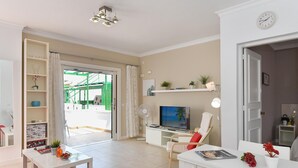 A modern living room with a TV, a dining area, and a balcony with a view. - Central Apartment With Spectacular Terrace-formerly TUI Ferienhaus (San Bartolomé de Tirajana)