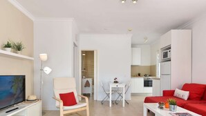 A modern living room with a TV, a red sofa, a dining area, and a kitchen. - Central Apartment With Spectacular Terrace-formerly TUI Ferienhaus (San Bartolomé de Tirajana)