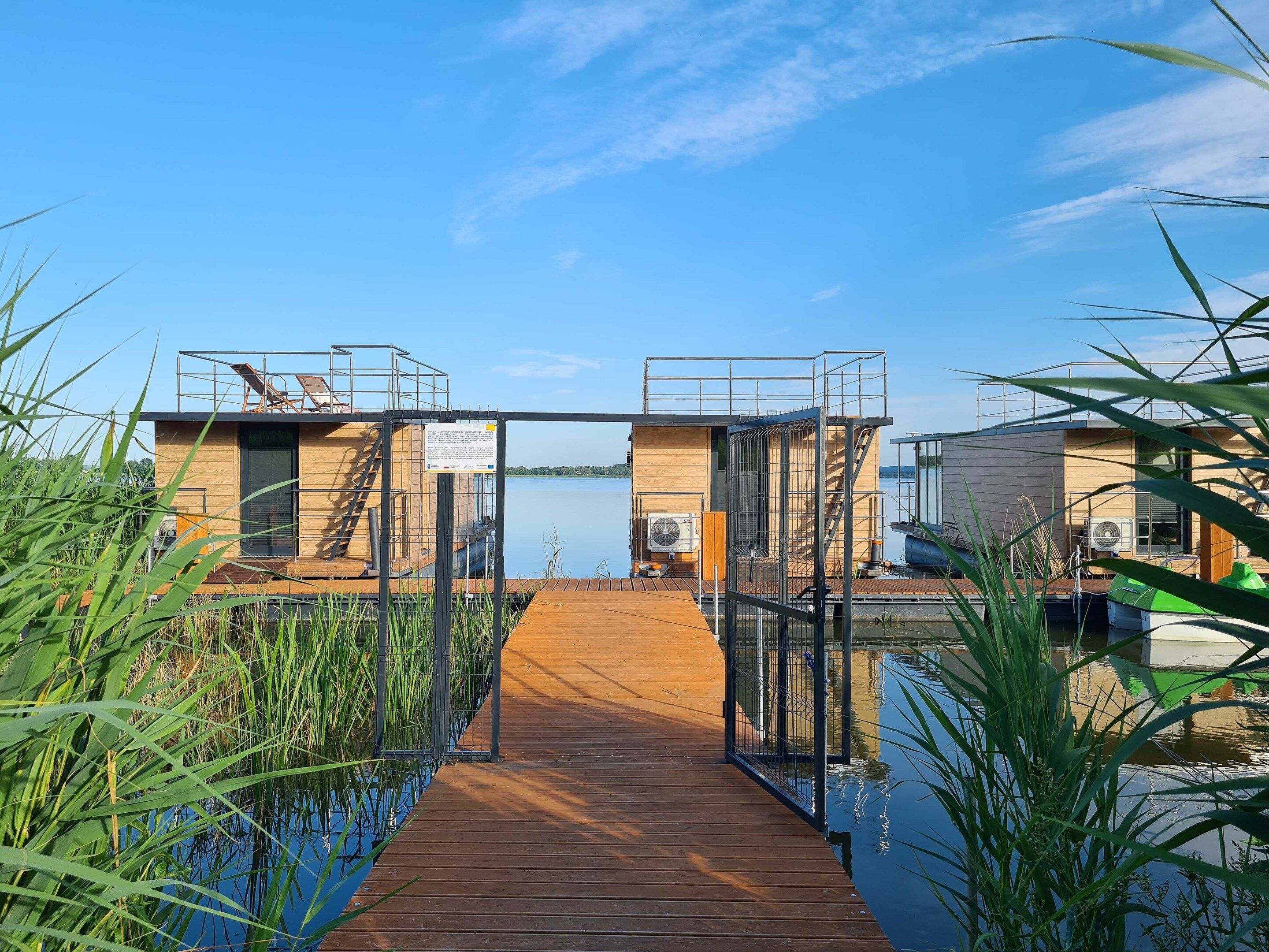 A wooden dock leading to a modern building with a view of a calm lake.