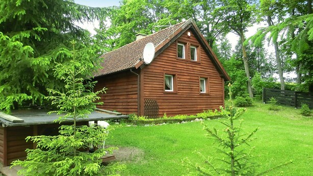 Une cabane en bois avec un toit en pente, une antenne parabolique et une petite terrasse.