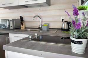A modern kitchen with a stainless steel sink, a kettle, and a potted lavender plant. - Holiday Homes Close to the Seaside Beach (Darlowo)