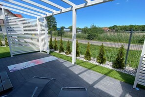 An outdoor patio area with a pergola structure, a paved floor, and a view of a road and greenery. - Holiday Homes Close to the Seaside Beach (Darlowo)
