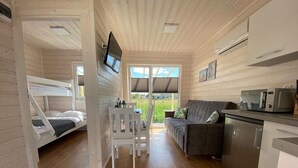 A cabin interior with a bunk bed, a sofa, a dining table, and a kitchenette. - Holiday Homes Close to the Seaside Beach (Darlowo)