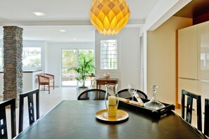 A dining area with a stone pillar, a table with a candle, and a hanging light fixture. - Villa With Pool and Extravagant Architecture (Ingenio)