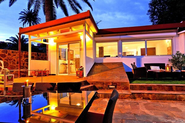 A modern house with a swimming pool, outdoor seating, and a stone wall. - Villa With Pool and Extravagant Architecture (Ingenio)