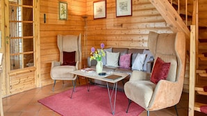 Interior acolhedor de uma cabana com escada de madeira, um sofá e uma mesa de centro.