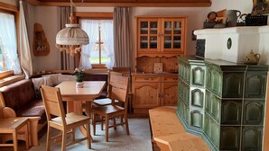 A cozy cabin interior with a wooden dining table, chairs, a bench, a green cabinet, and a window with curtains. - Holiday Home, Krimml (Krimml)