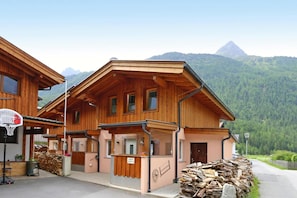 Un chalet in legno con canestro da basket, un piccolo spazio relax all'aperto e vista su una montagna.