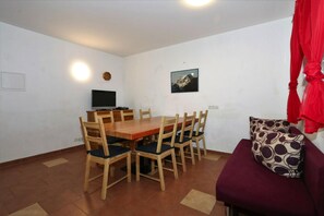A dining area with a wooden table and chairs, a television, and a mountain painting on the wall. - Terraced Houses Oliver, Langenfeld (Laengenfeld)