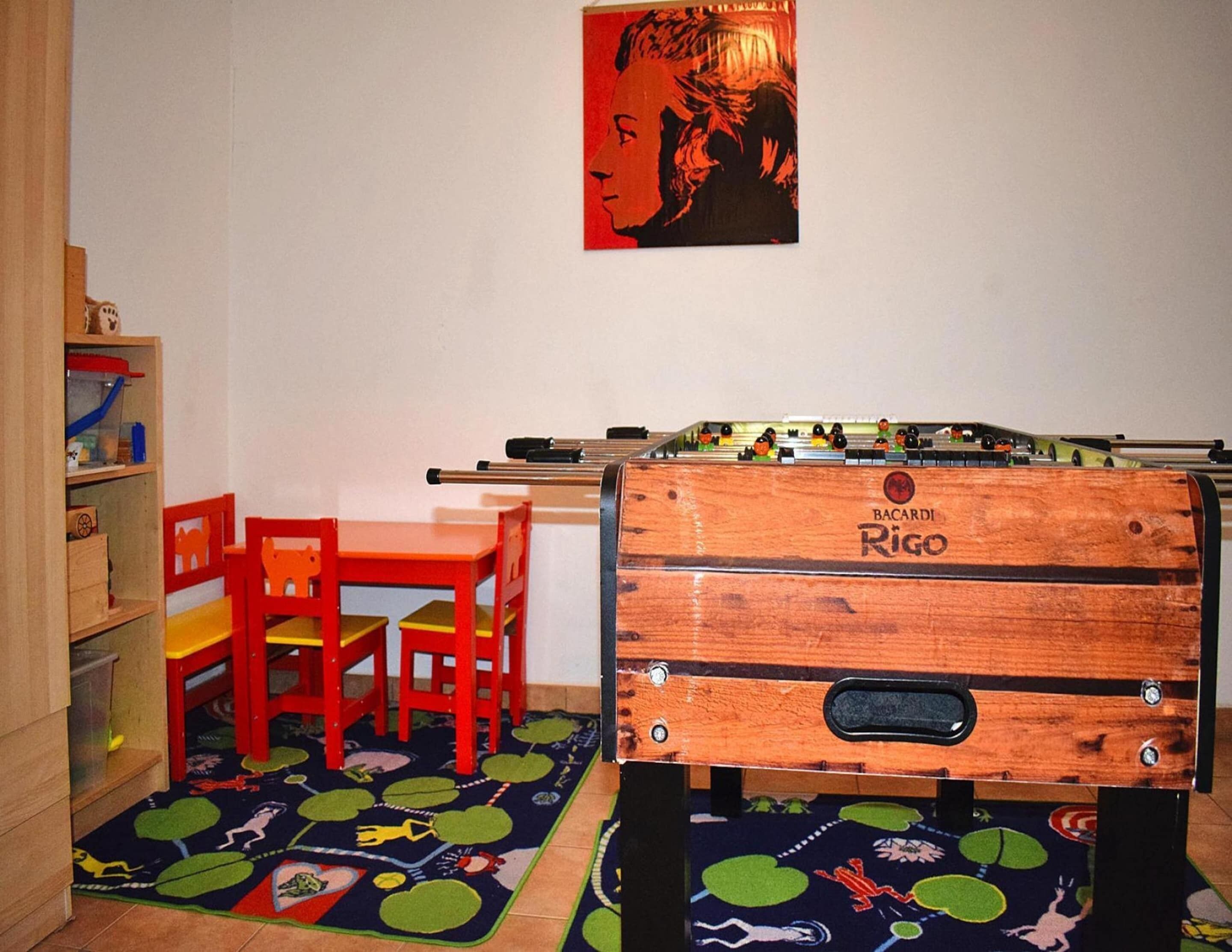 Un área de juegos infantiles con mesa de fútbol de mesa, una silla roja y una estantería.