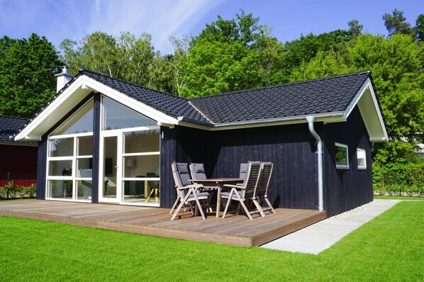 Enter a serene setting through the large glass door, surrounded by lush green lawns and mature trees.