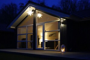 Une maison moderne dotée de grandes fenêtres en verre et d’un toit en pente.