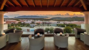 A terrace with wicker furniture and a view of a town and mountains. - Appartement Grande Baia Resort, San Teodoro (San Teodoro)
