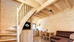 Ein Holzinnenraum mit Treppe, Fernseher, Essbereich und einer Couch.