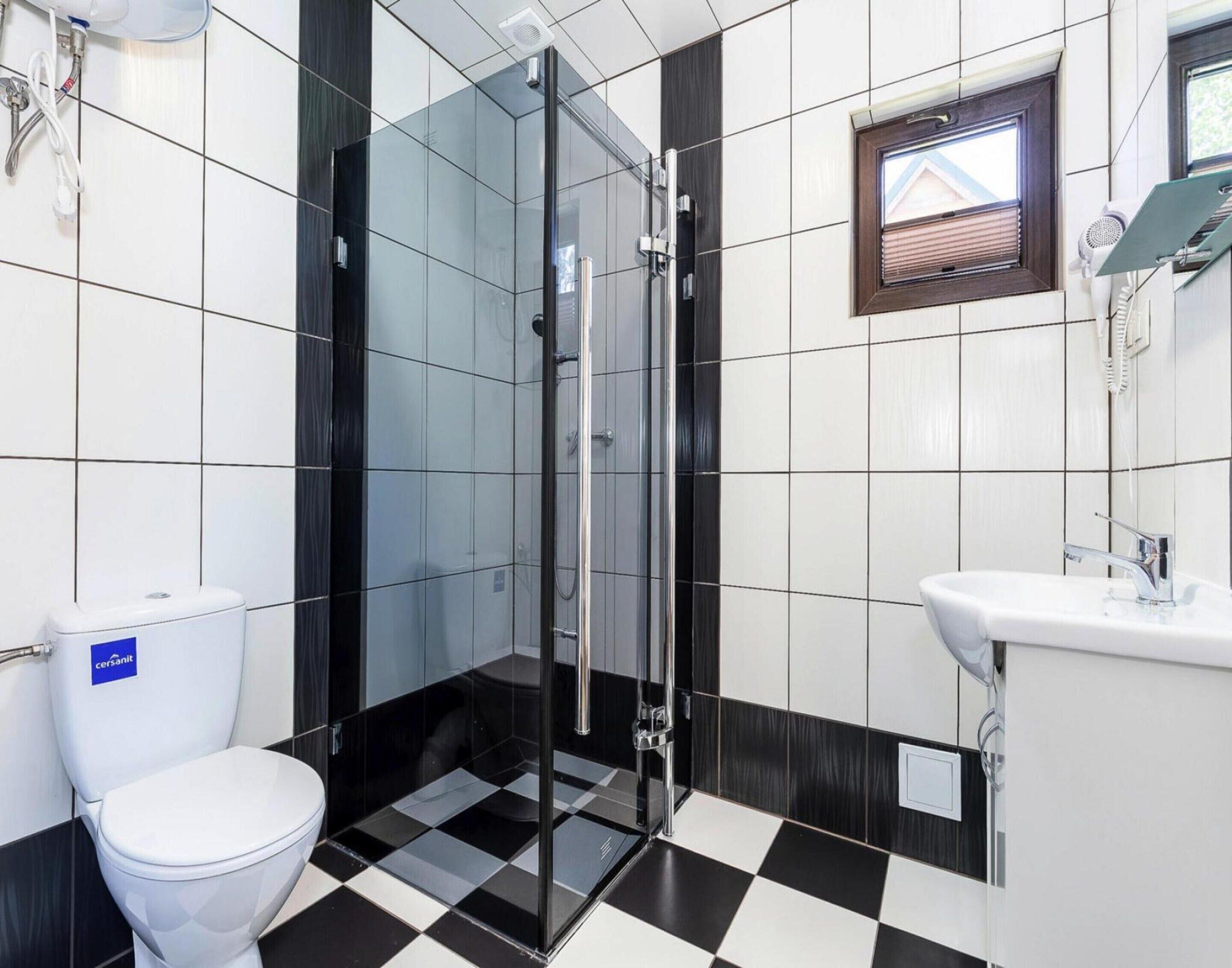 Een moderne badkamer met een douchecabine van glas, een wit toilet en een wastafel met spiegel.