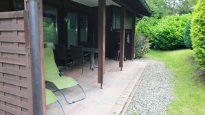 A covered patio with a brick floor, outdoor furniture, and a view of a garden. - Ferienhaus in der Nahe des Sees, Haustierfrei (Clausthal-Zellerfeld)