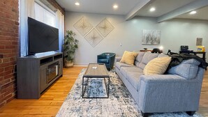A living room with a TV, sofa, coffee table, and decorative wall art.