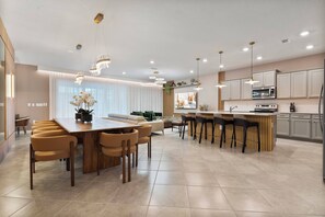 Et moderne køkken med en central ø, spiseområde med stole og en bar med barstole.
