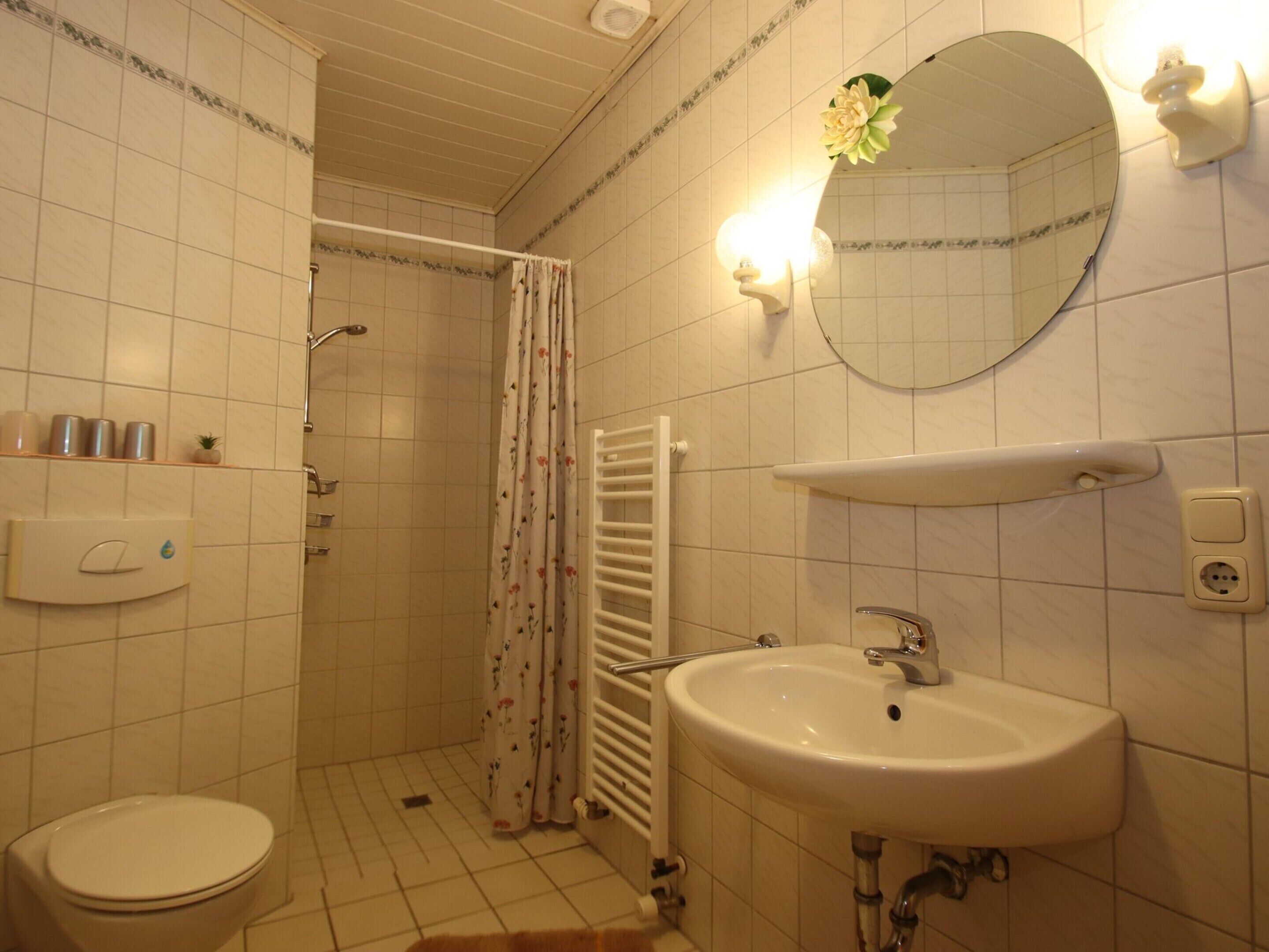 Une salle de bain comprenant des toilettes, un lavabo, une douche et un miroir.