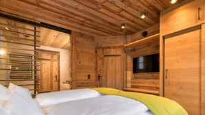 Una habitación tipo cabaña de madera con dos camas, un televisor y una puerta corrediza.
