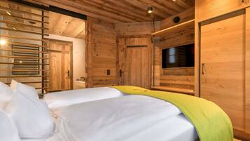 A wooden cabin-style room with two beds, a TV, and a sliding door.