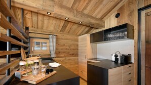 Una cocina moderna con vigas de madera, encimera negra y estante empotrado para vinos.