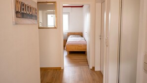 Un pasillo que conduce a un dormitorio con una cama, un espejo y un letrero que dice 'WELCOME'.