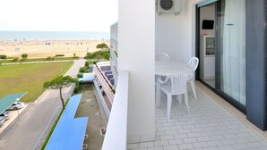 Ein Balkon mit Tisch und Stühlen mit Blick auf einen Strand.