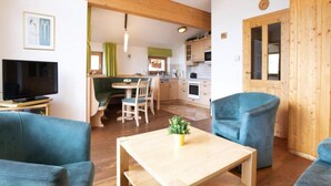 A cozy living room with a wooden coffee table, blue sofas, and a TV on a stand. - Chalet in Hohe Tauern With Panoramic Views (Wald im Pinzgau)