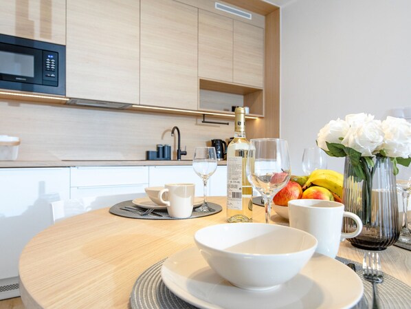 Une cuisine moderne avec des meubles en bois, un four à micro-ondes et un coin repas avec une table dressée pour deux personnes.