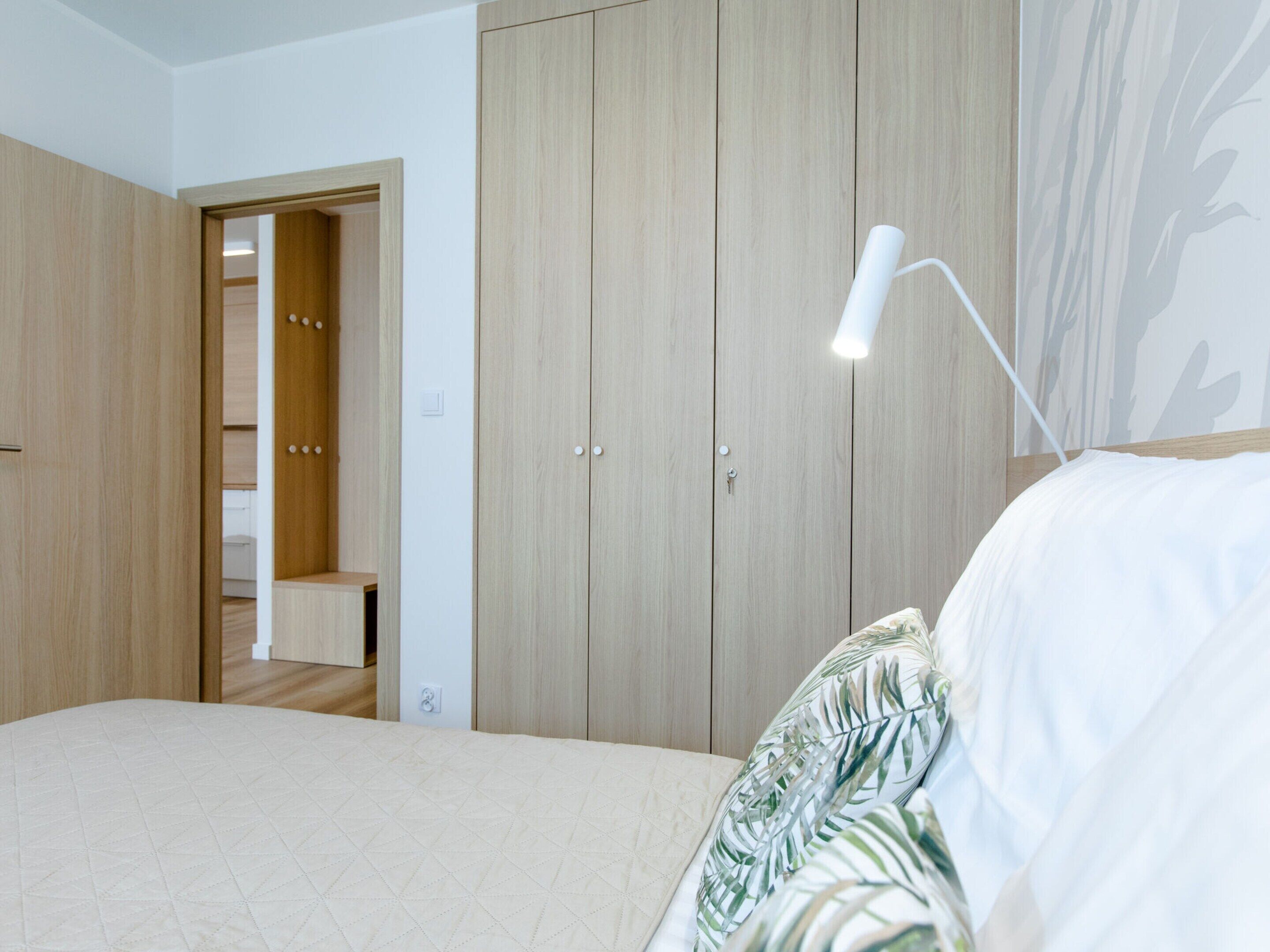 A bedroom with a bed, a nightstand, a bedside lamp, and a wardrobe.