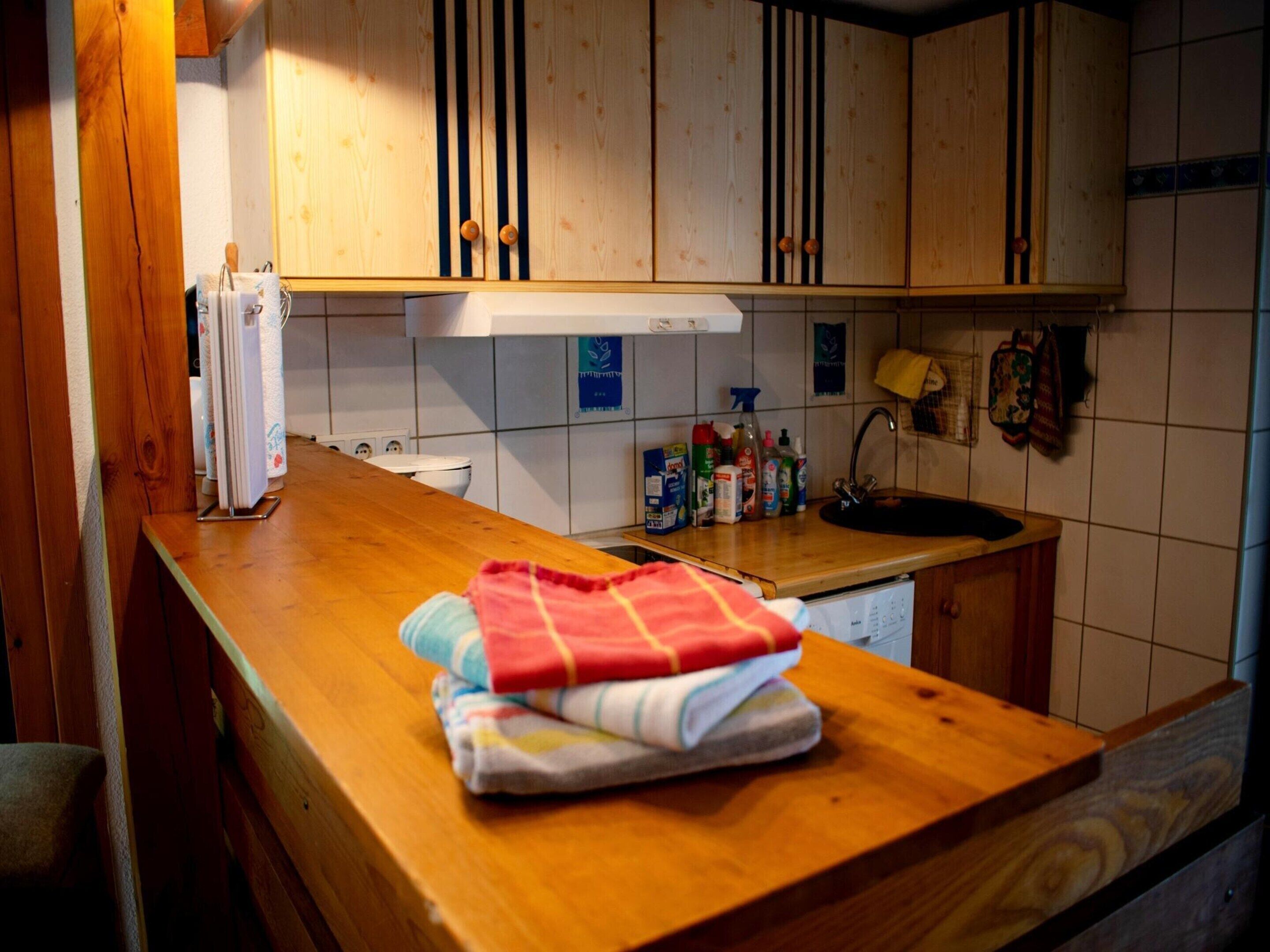 Cucina con mobili in legno, piano di lavoro in legno, lavandino e diversi oggetti da cucina.