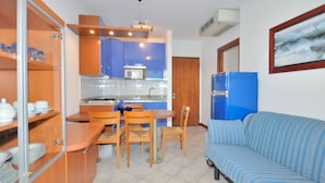 A compact living space with a kitchenette, a dining area, and a sofa. - Apartment in Bibione Near Beach and Pool (San Michele al Tagliamento)