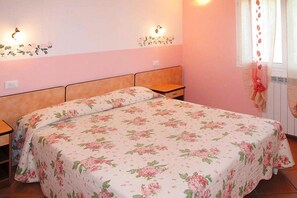 Cozy bedroom with a double bed, floral-patterned bedspread, and a floral wallpaper design.