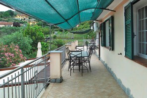 Enjoy a serene view of the lush garden from this balcony, complete with a shaded seating area and comfortable chairs.
