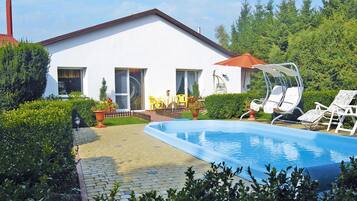 A modern house with a swimming pool, outdoor seating, and a well-maintained garden.