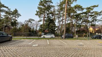 Un estacionamiento con pavimento estampado, rodeado de árboles y una valla.