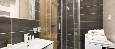 A modern bathroom with a glass-enclosed shower, a white sink, and a towel rack.