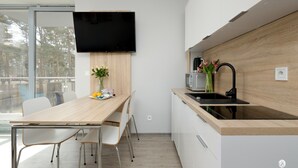 Eine moderne Küche mit Holzarbeitsplatte, integriertem Spülbecken und einem flachbildfernseher an der Wand.