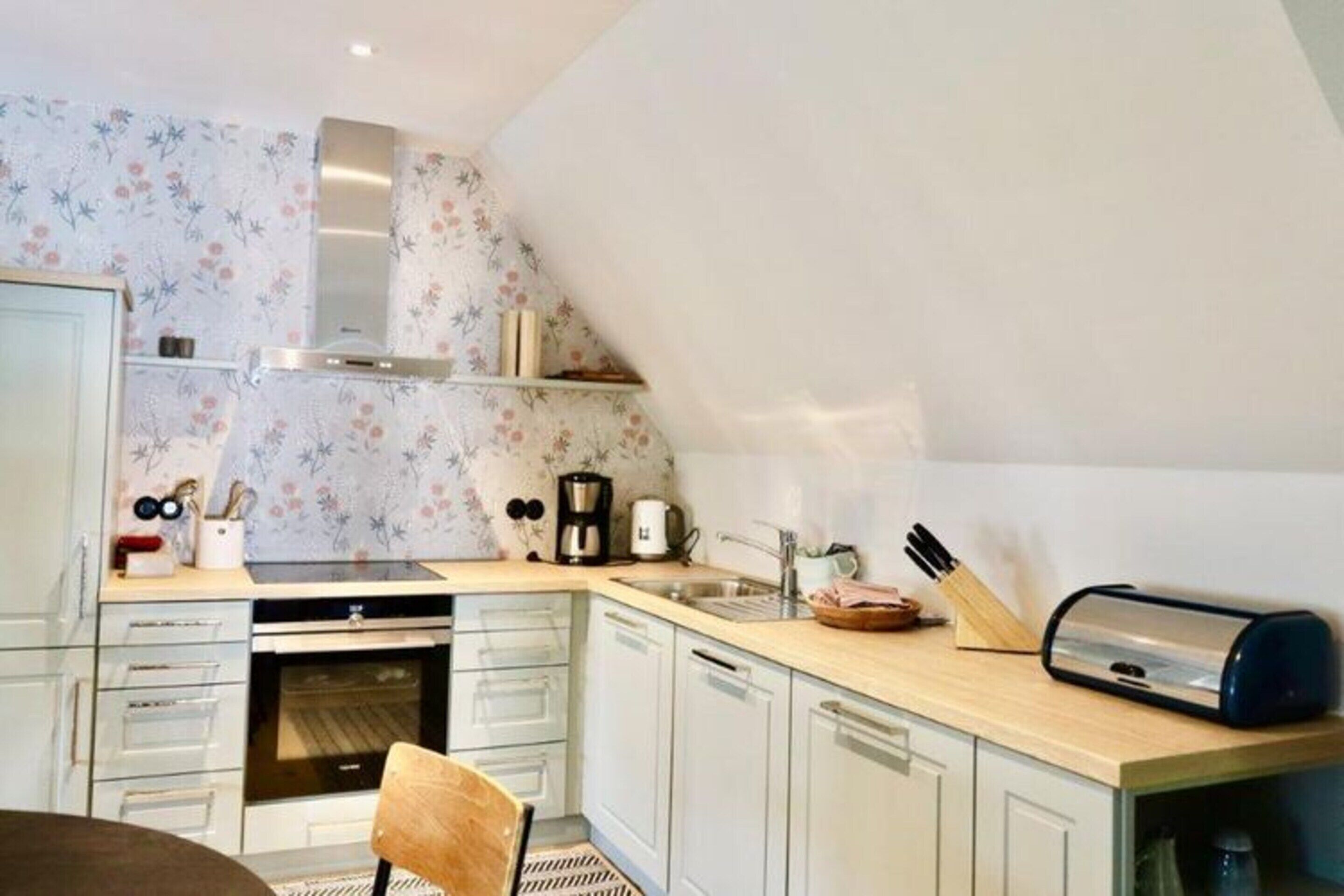 A modern kitchen with white cabinets, a wooden countertop, and a built-in oven.