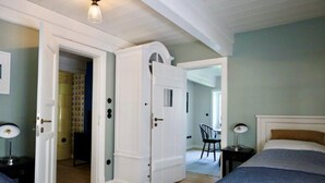 A bedroom with two beds, a wardrobe, and a chair. - Reetgedecktes Ferienhaus in Nieblum auf Foehr (Nieblum)