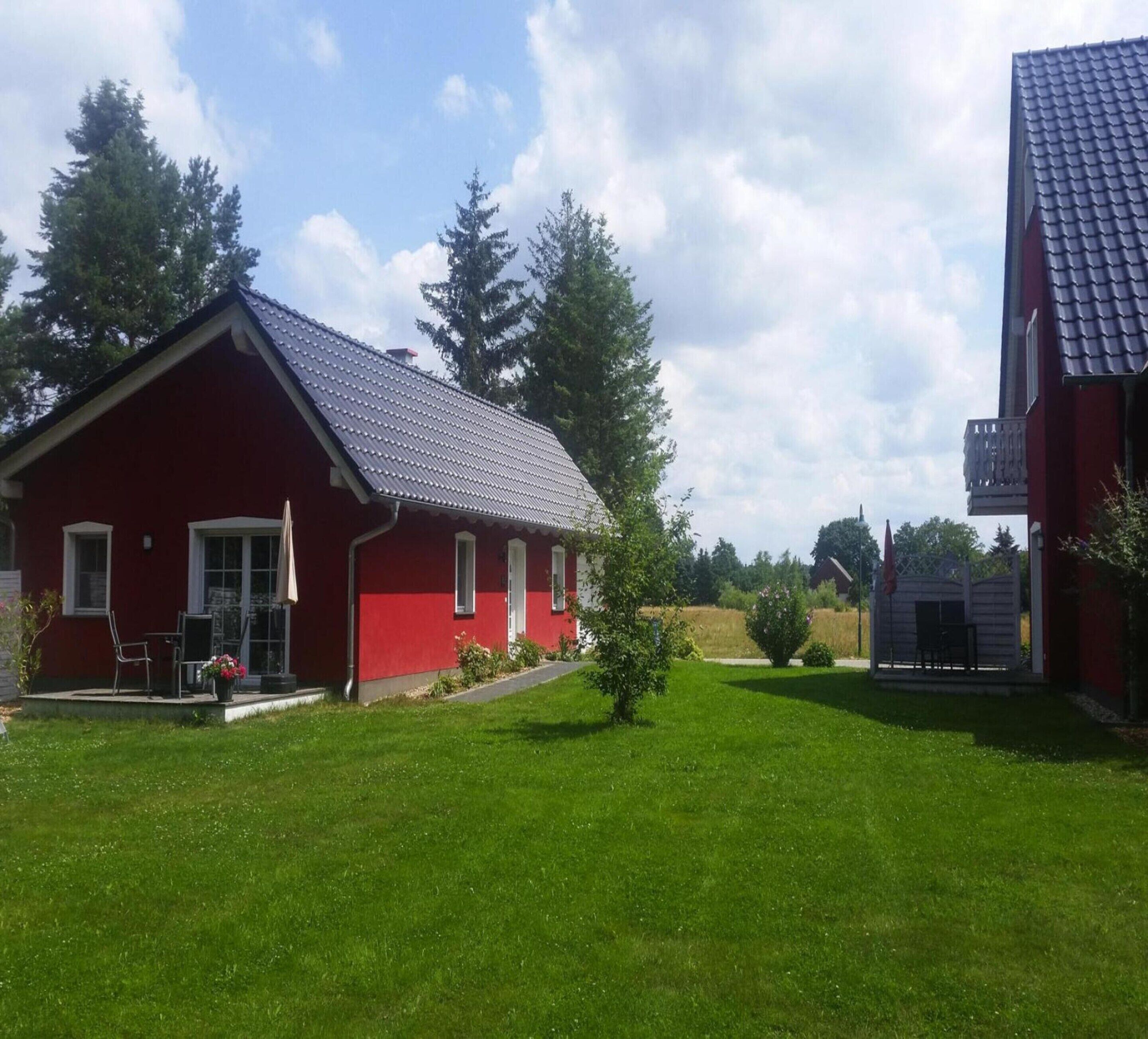 A red building with a sloped roof, a small porch, and a lawn in front.