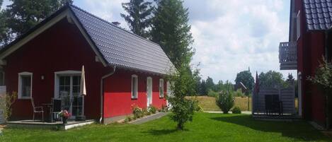 A red building with a sloped roof, a small porch, and a lawn in front.