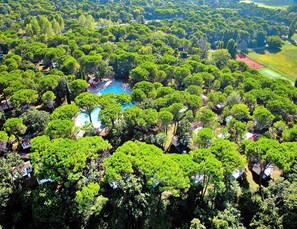 An aerial view of a residential area with a swimming pool surrounded by lush greenery and houses. - Bungalow in the Residence Belvedere in Grado (Aquileia)
