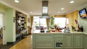 A spacious kitchen with a central island, a built-in stove, and a large window with curtains. - Holiday Home, Maspalomas (San Bartolomé de Tirajana)