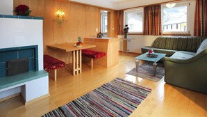 Una sala de estar con un banco de madera, un sofá, una mesa de comedor con banco y una chimenea.