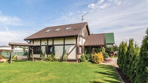 A two-story house with a sloped roof, a covered porch, and a well-maintained lawn. - Comfortable Holiday Home With Garden, by the Lake (gmina Będzino)