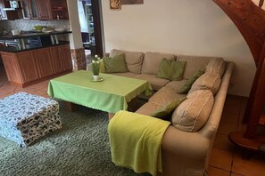 Een woonkamer met een bank, een klein tafeltje en een keuken op de achtergrond.
