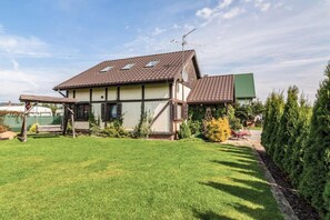 Een tweelaags huis met een schuin dak, een zichtbare schotelantenne en een verzorgd gazon.