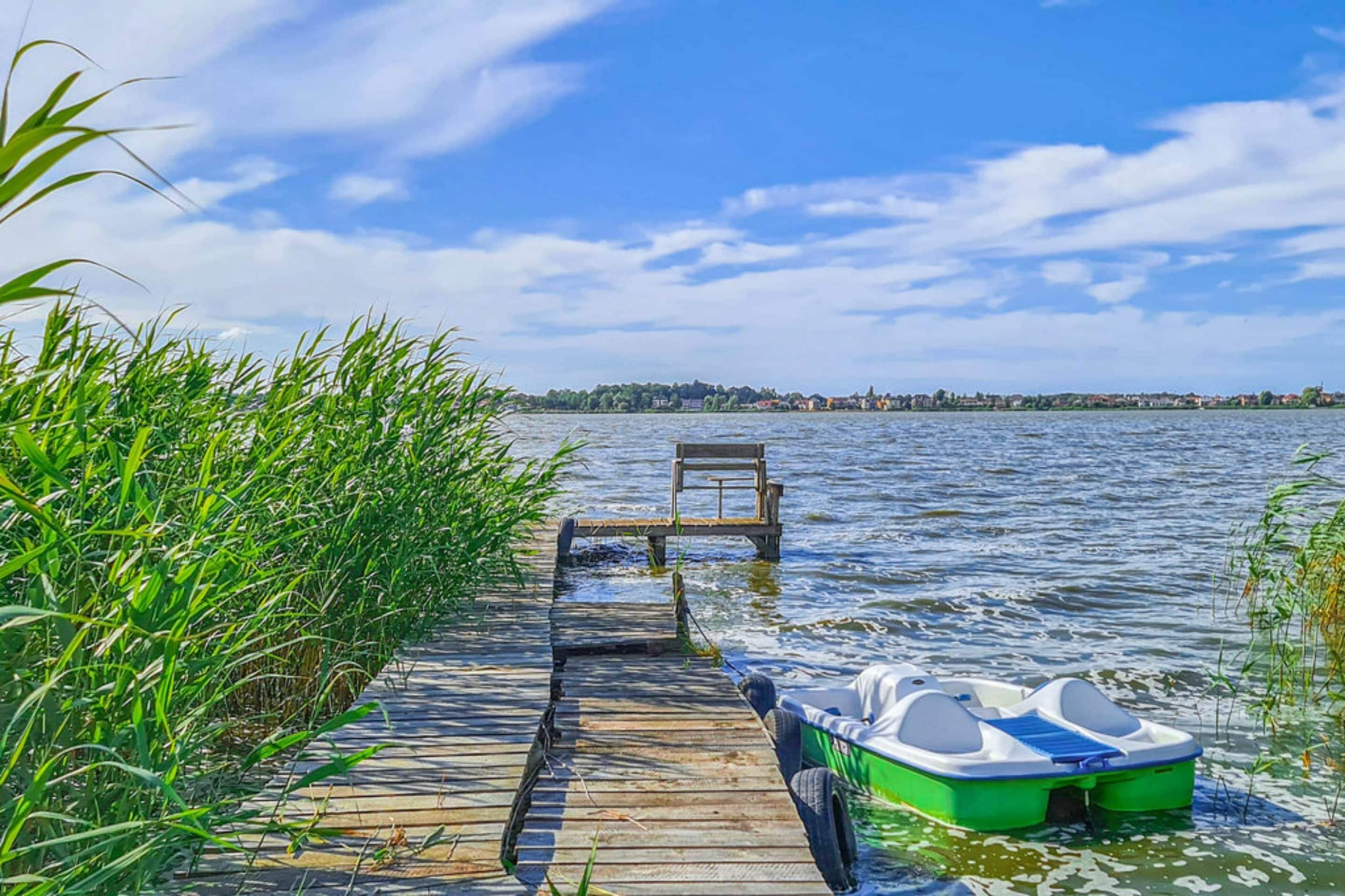 A wooden dock extending into a lake with a rowboat and a bench.